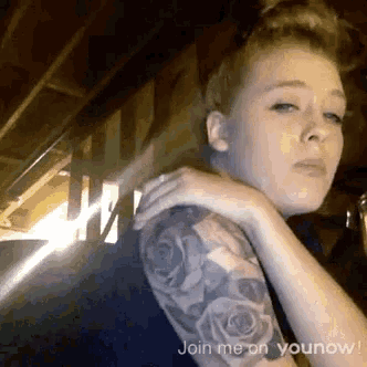 a woman with a tattoo on her arm has the words join me on younow on the bottom
