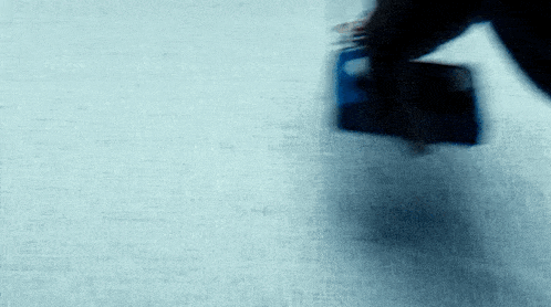 a blurred image of a person carrying a blue briefcase
