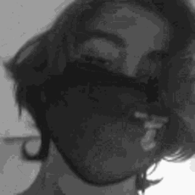 a black and white photo of a woman wearing sunglasses and a white shirt .