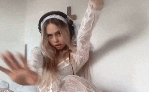 a woman in a white dress and headphones is dancing in front of a cross