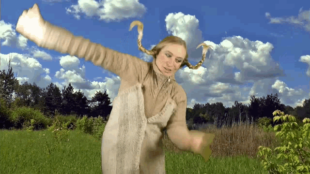 a woman with pigtails is dancing in a field with her arms outstretched