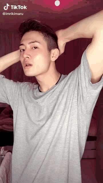 a man in a grey t-shirt has a tiktok sticker on his shoulder