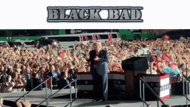 a man stands on a stage in front of a crowd with the words black bad on the bottom