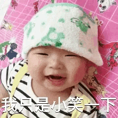 a baby wearing a green hat is smiling and making a face .