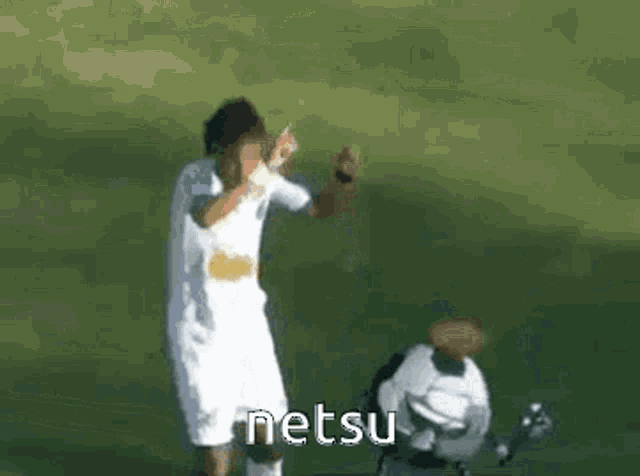 a man in a white shirt and shorts is standing next to a soccer ball with the word netsu written on it .