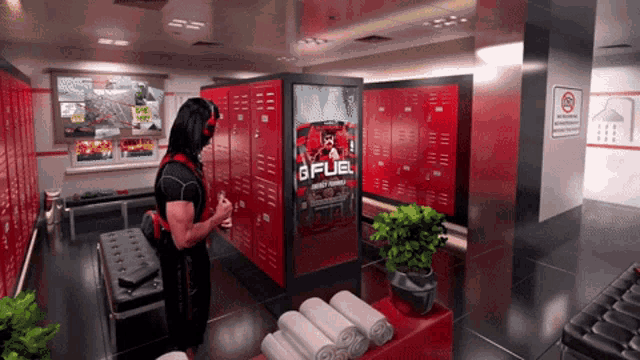 a man stands in a locker room with a gfuel advertisement on the wall