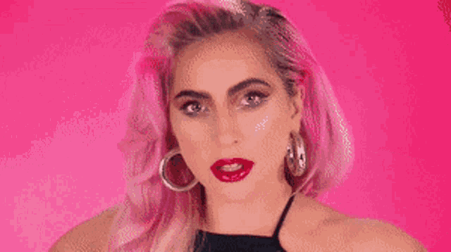 a woman with pink hair is covering her face with her hands .