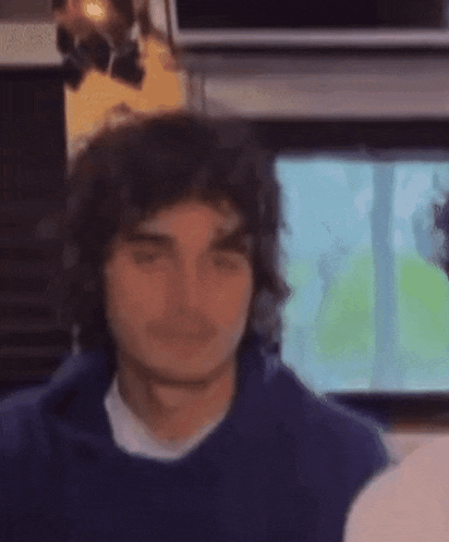 a young man with curly hair is wearing headphones and a blue hoodie .