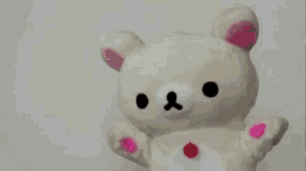 a white teddy bear with pink stickers on its face
