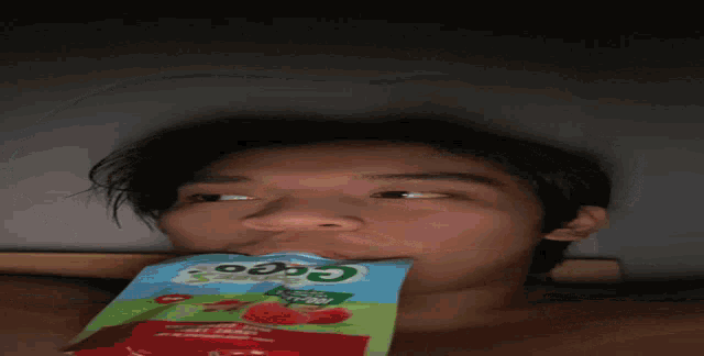 a young boy is drinking from a bag that says coco