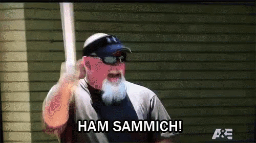 a man with a beard is holding a baseball bat and says ham sammich