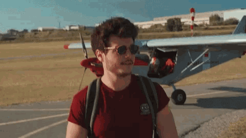 a man wearing sunglasses is standing in front of a small plane with the letters a and b on it