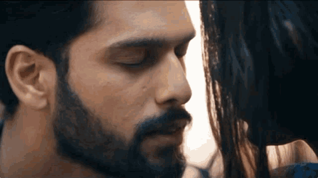 a man with a beard and a woman with long hair are kissing