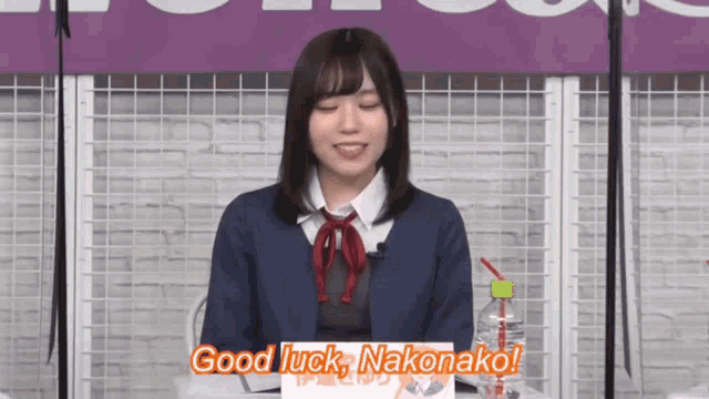 a girl sitting in front of a sign that says good luck
