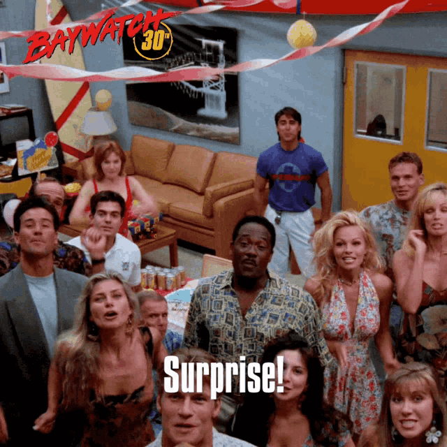 a group of people are gathered in a room with baywatch 30 written on the wall behind them