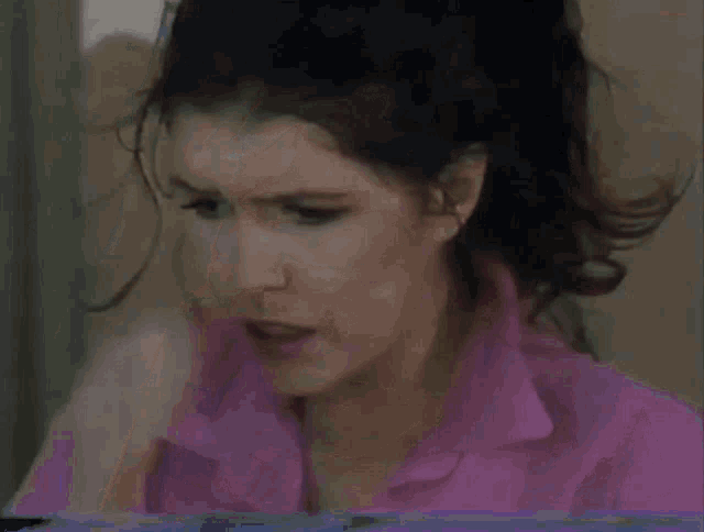a woman in a pink shirt has her hand on her head