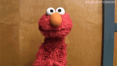 elmo from sesame street standing in front of a wooden wall