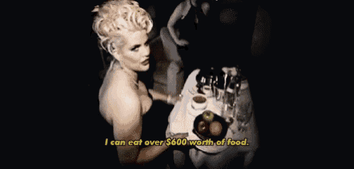 a woman is sitting at a table holding a tray of food and saying i can eat over $ 600 worth of food