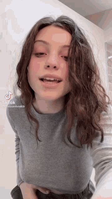 a young woman with long brown hair is taking a selfie with her mouth open .