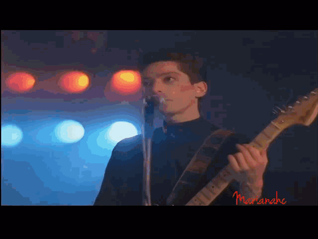 a man playing a guitar and singing into a microphone with the name marianne in red