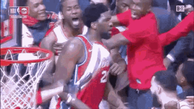 a basketball player is being attacked by a crowd of people while playing a game of basketball .
