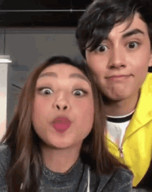 a boy and a girl are making funny faces for a picture .