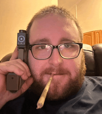 a man with glasses holds a gun in his hand