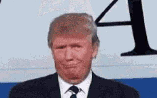 donald trump is wearing a suit and tie and making a face .