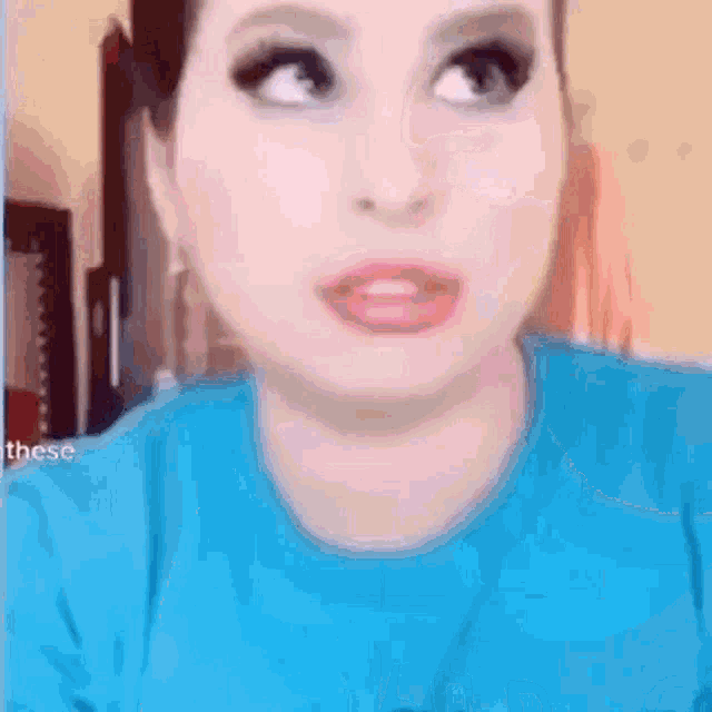 a close up of a woman 's face wearing a blue shirt .