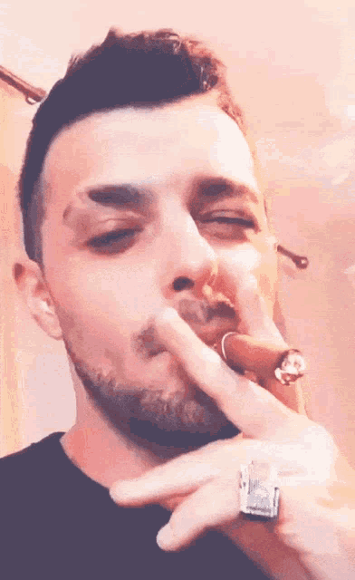 a man is smoking a cigar with a ring on his finger