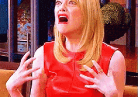 a woman in a red dress is sitting on a couch with her mouth open .
