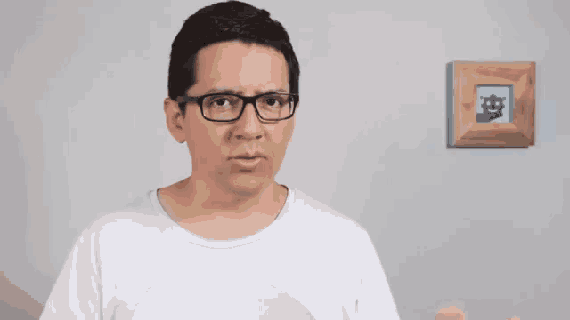 a man wearing glasses stands in front of a picture of a robot