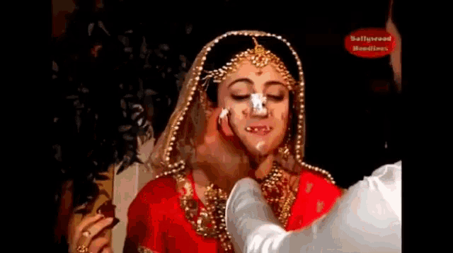 a bride with a lot of makeup on her face is being kissed by a man .