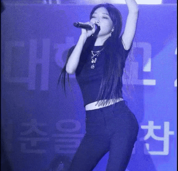 a woman singing into a microphone in front of a sign that says ch