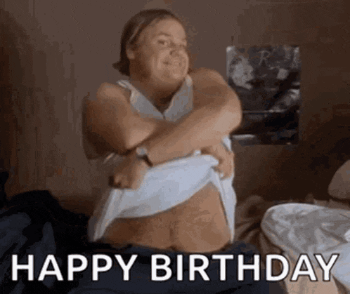 a woman is sitting on a bed taking off her shirt and says `` happy birthday '' .