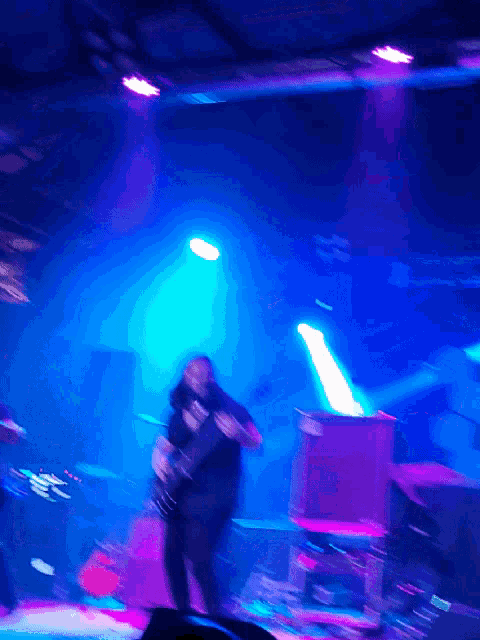 a blurry image of a man playing a guitar in a dark room