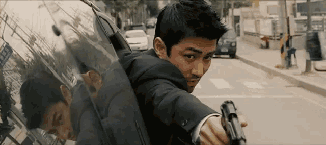 a man in a suit is pointing a gun at a car