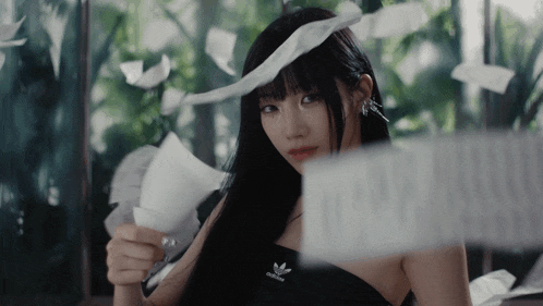 a woman holding a piece of paper with the word adidas on it