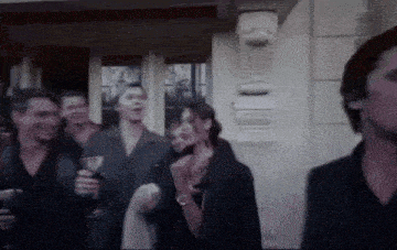 a group of people are standing outside of a building holding wine glasses .