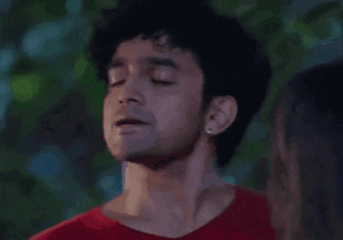 a man in a red shirt is standing next to a woman with his eyes closed and his mouth open .