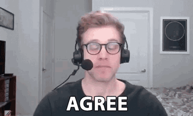 a man wearing headphones and a microphone is making a funny face and saying `` agree '' .