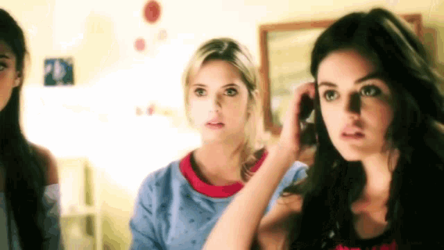 three women are standing next to each other and one of them is talking on her phone