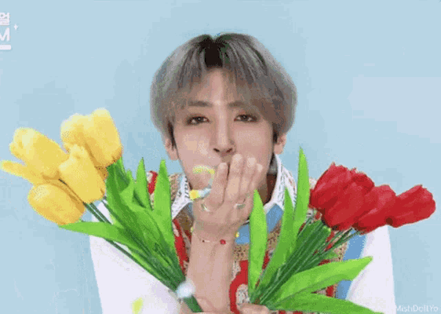 a man is blowing a kiss while holding a bouquet of flowers in his hands .