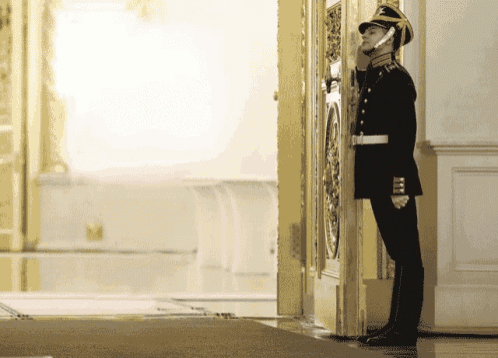 a man in military uniform is standing in front of a door