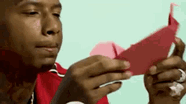 a man is holding a piece of red paper in his hands