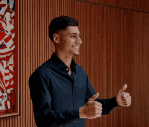a man in a black shirt is giving a thumbs up sign
