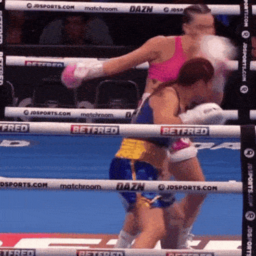 two female boxers are fighting in a boxing ring sponsored by betfred and dazn