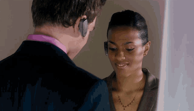 a man in a suit and a woman in a necklace are looking at each other
