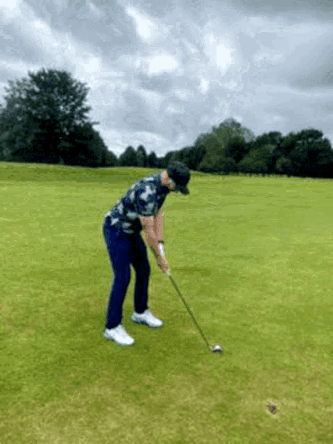 a man is swinging a golf club at a golf ball .