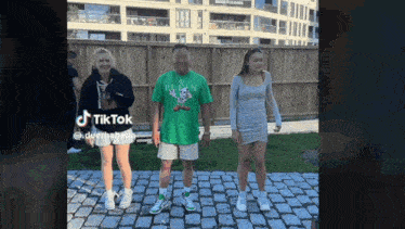 a man and two women are standing next to each other on a cobblestone driveway .